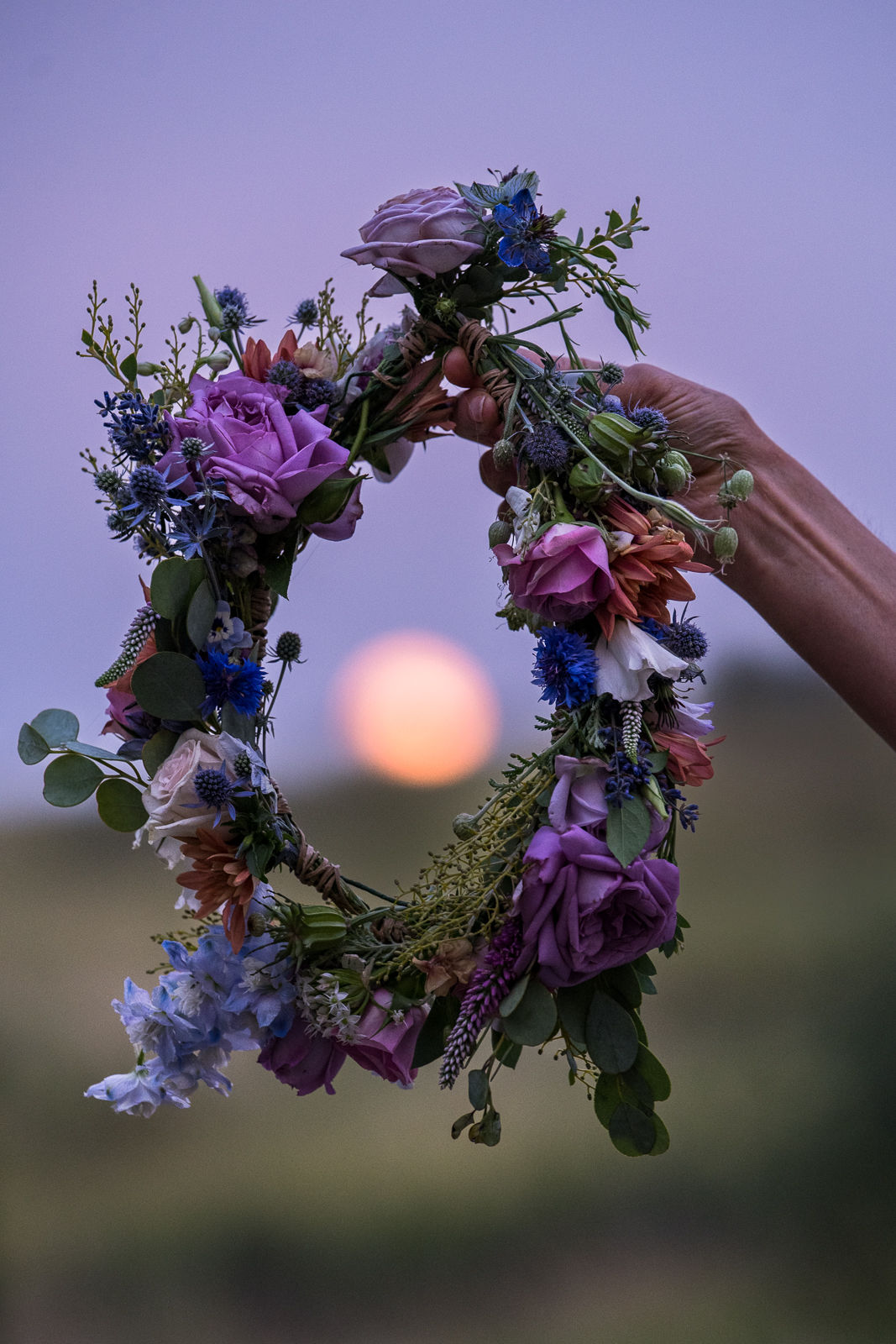 A flower crown held up around the full moon