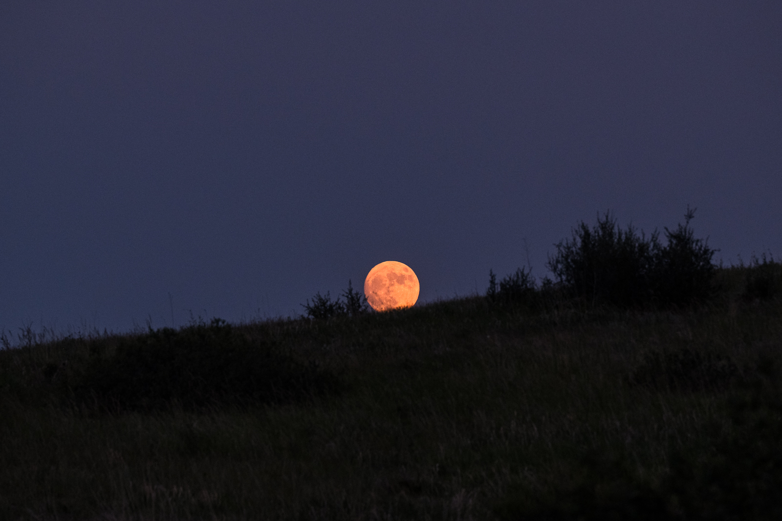 The full moon rising over the hills