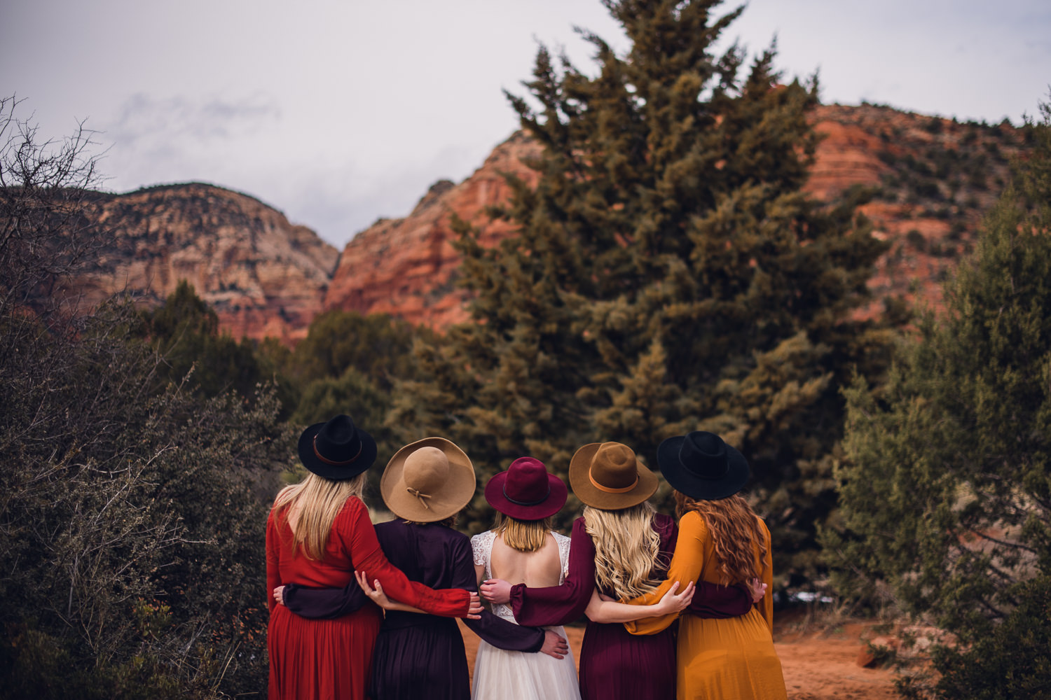 Five women arm in arm facing the Sedona red rocks