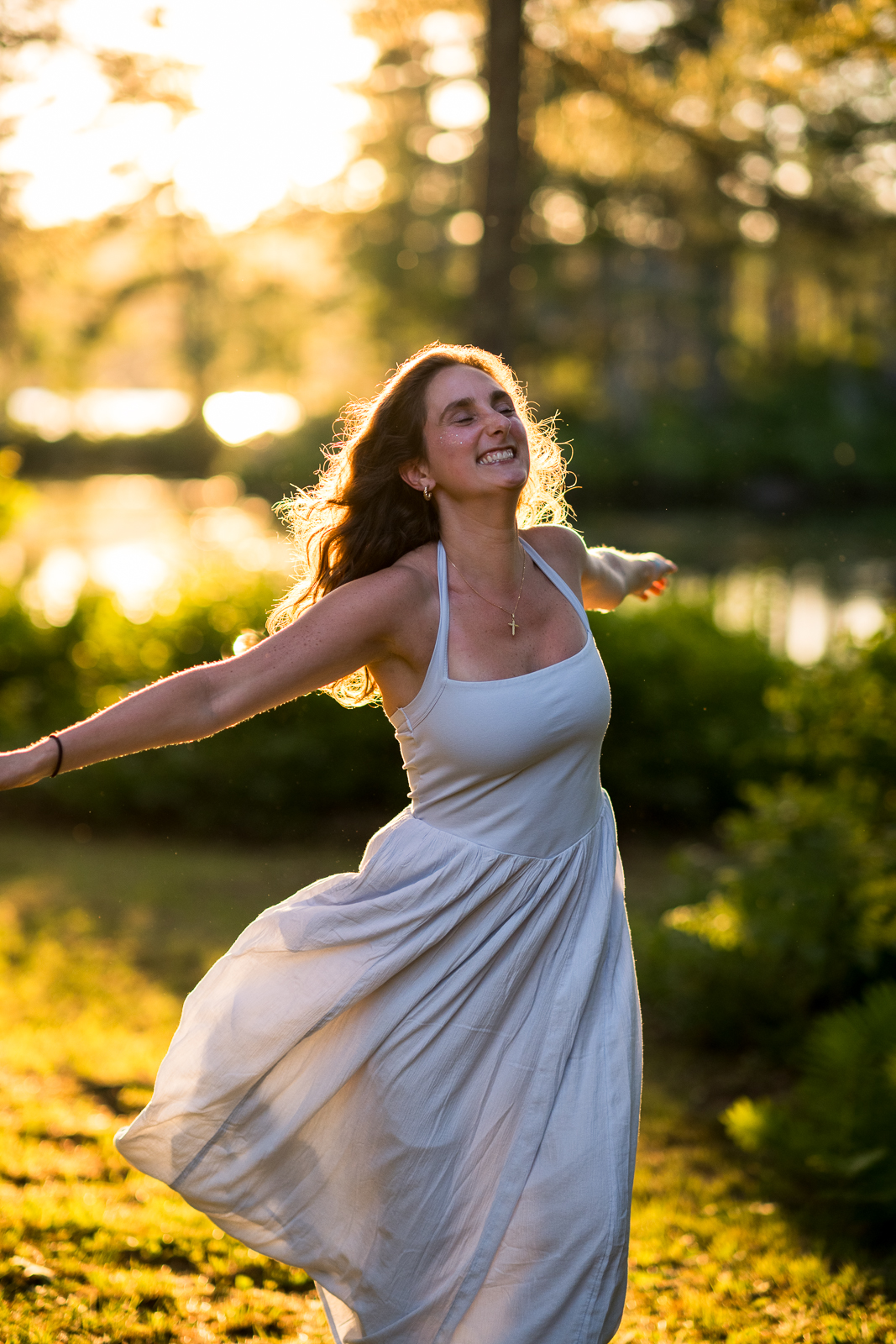Liv dancing in a white dress at golden hour by the lake